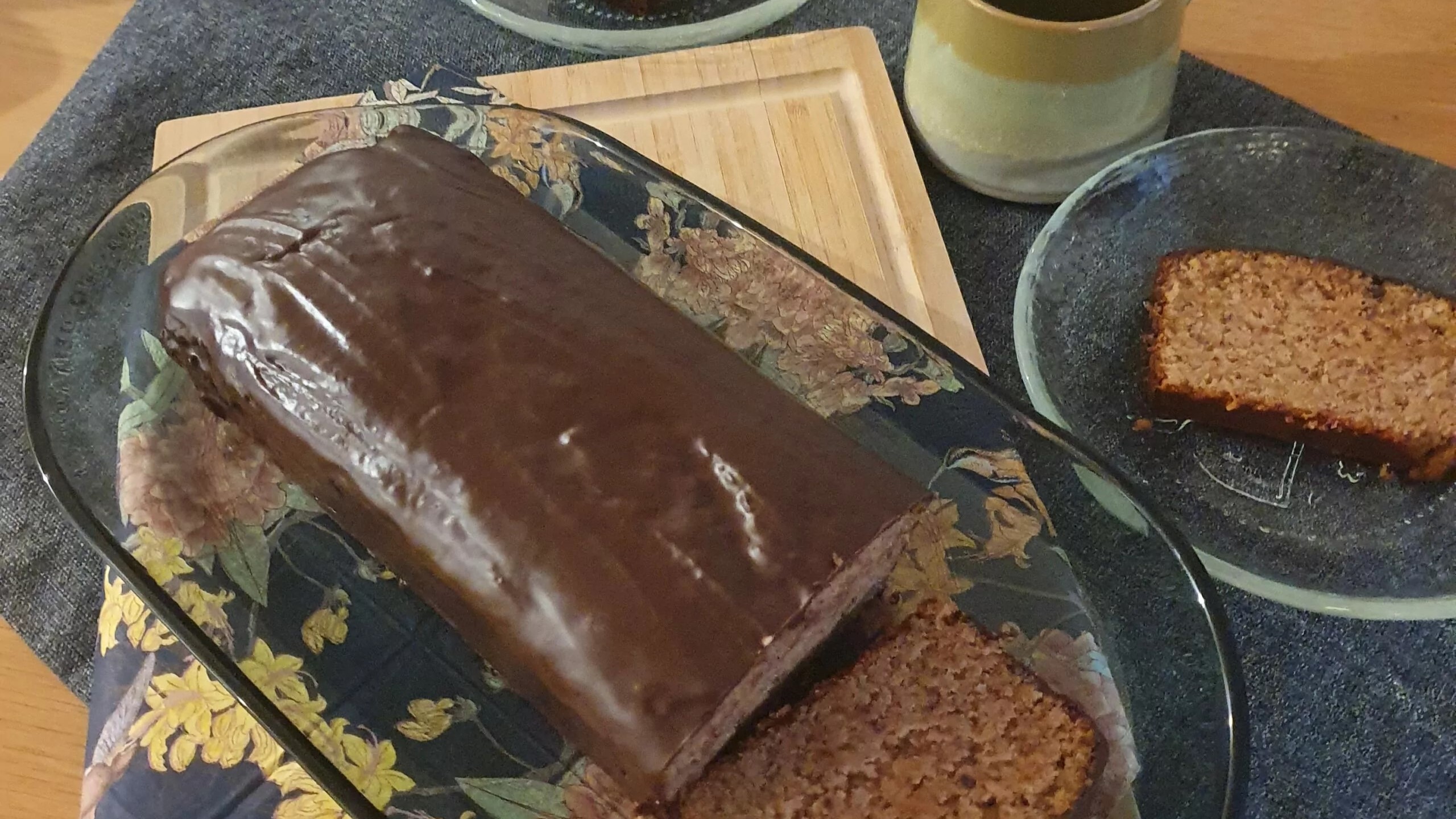 Marroni Cake mit Schokoladenglasur auf einem Tisch mit einem gschnittenen Stück Kuchen und einer Tasse Kaffee - FoodTrail, Blog