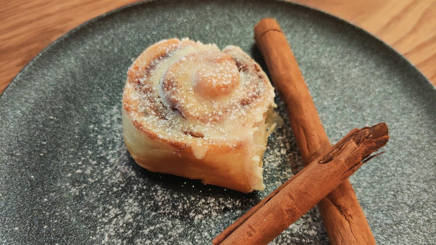 Bild einer Zimtschnecke auf einem Teller mit Zimtstangen - FoodTrail, Blog